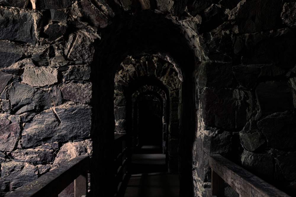 a dark tunnel with stone walls and railings
