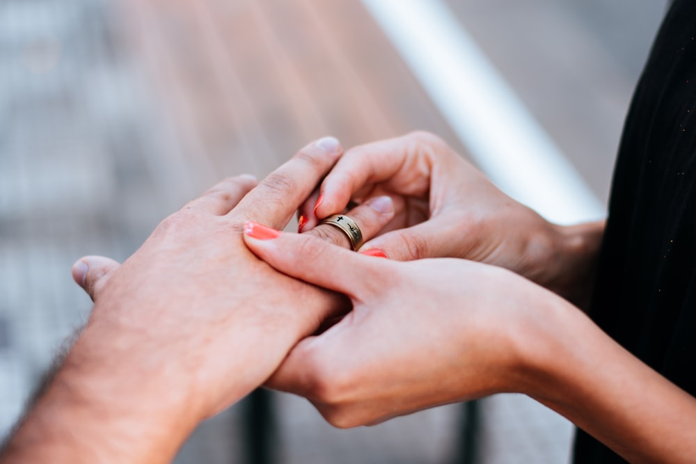 a man and a woman holding hands with a wedding ring