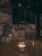 Close-up of a glowing Lumipétra candle with natural stones around it on a wooden table.