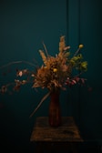 Close-up of a rustic wooden vase made from reclaimed wood with delicate dried flowers.