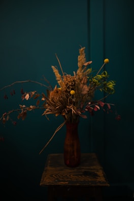 Close-up of a rustic wooden vase made from reclaimed wood with delicate dried flowers.