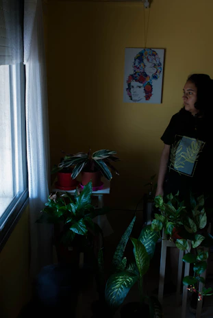 Portrait of Elizabeth in a softly lit room surrounded by potted plants and neutral tones.