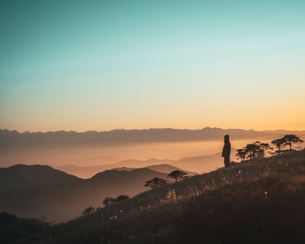 a person standing on top of a hill at sunset