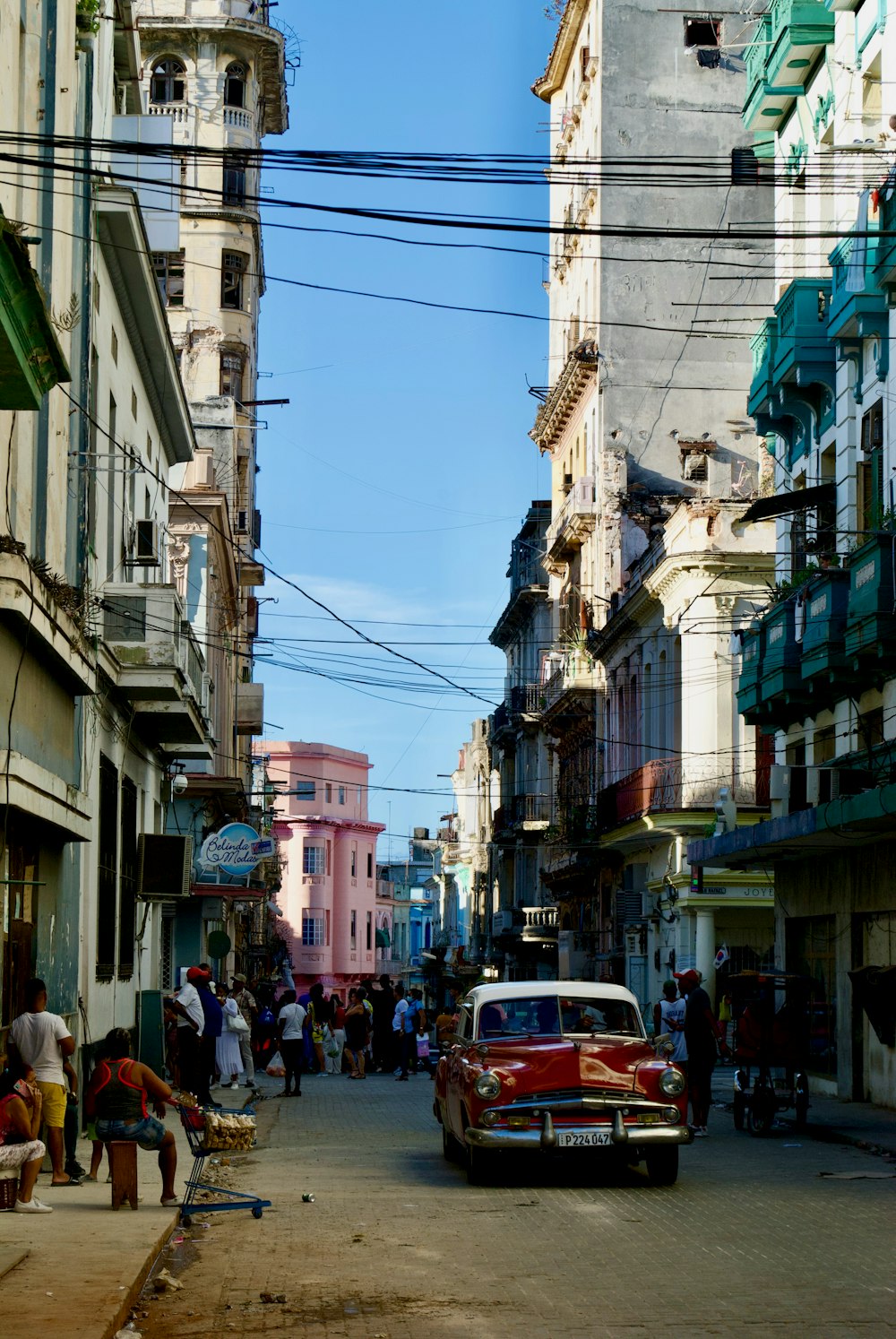 a red car driving down a street next to tall buildings