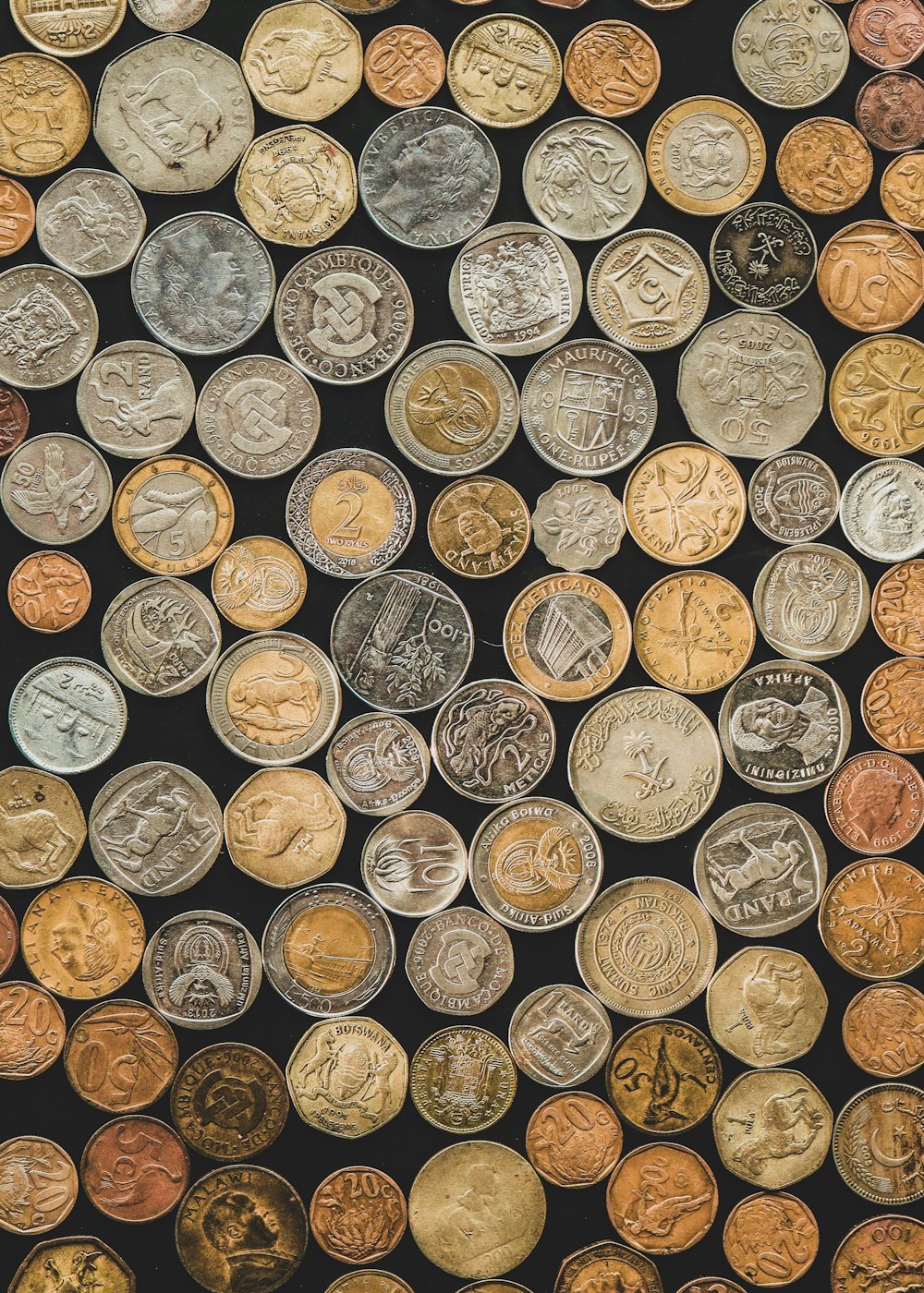 a bunch of different types of coins on a black background