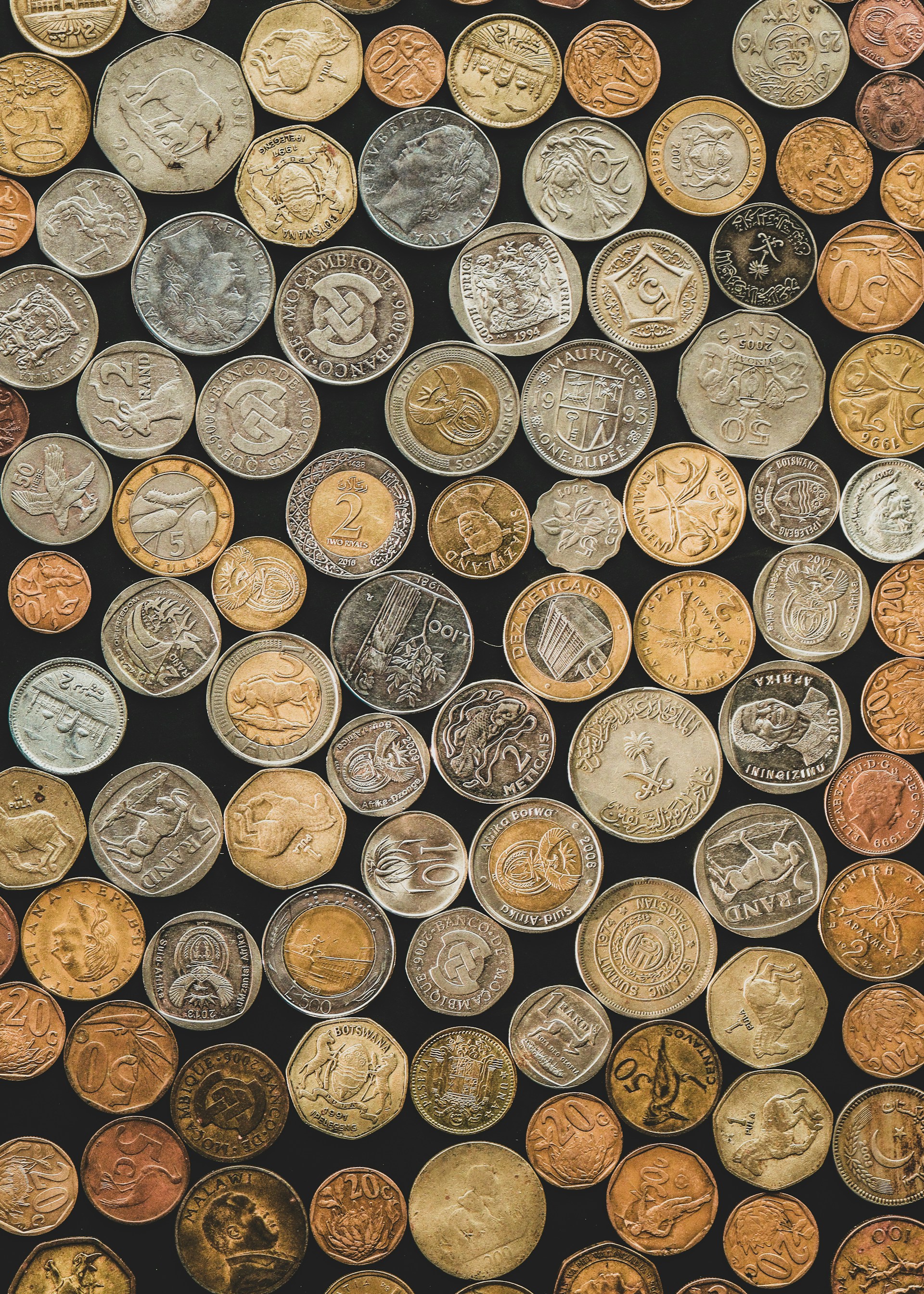 a bunch of different types of coins on a black background