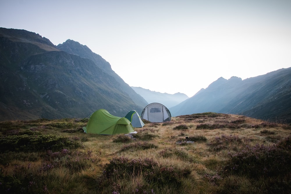 a couple of tents sitting on top of a lush green hillside