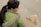 a woman in a green jacket petting a dog