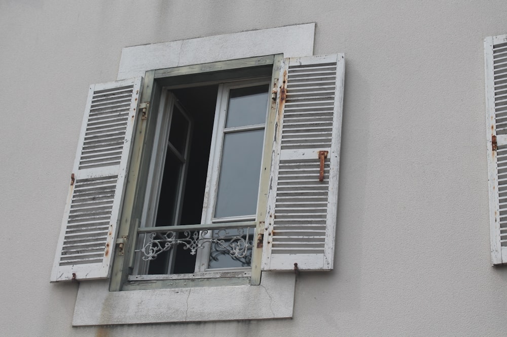 two windows with shutters open on a building