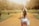 a woman walking down a dirt road carrying a purse