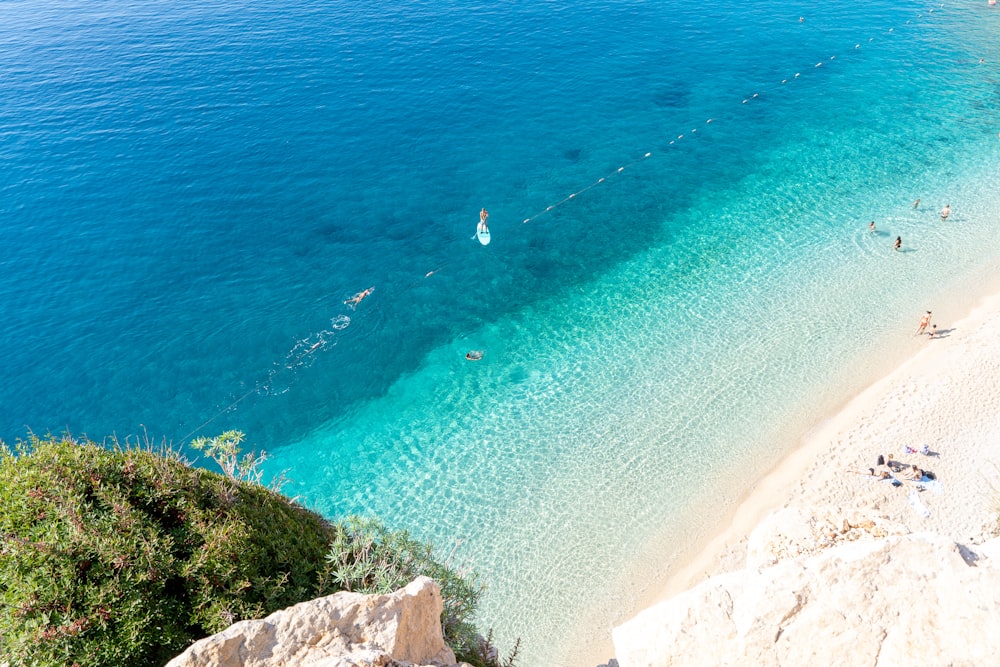 people are swimming in the clear blue water of a beach