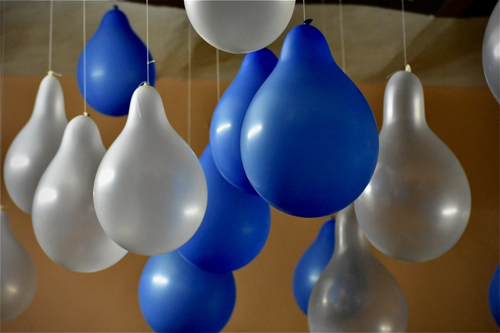 a bunch of blue and white balloons hanging from a ceiling