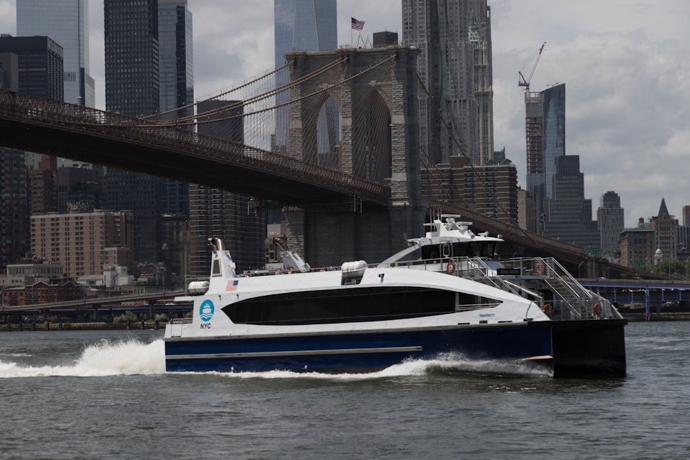 a blue and white boat traveling under a bridge