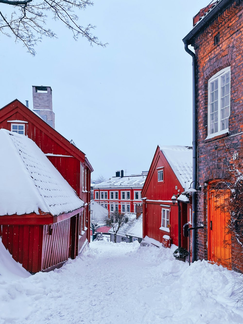 a snowy street with a red building in the background