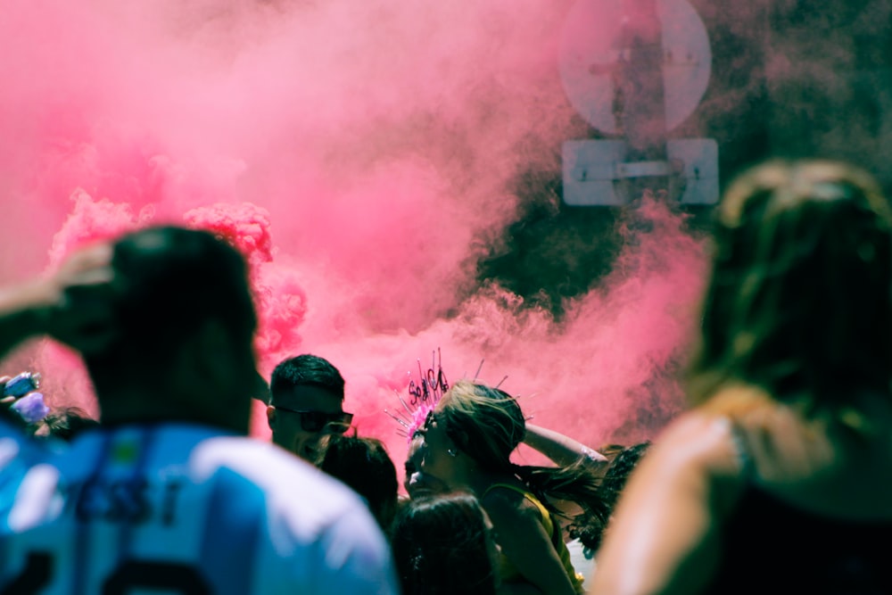 a group of people standing around a pink smoke bomb