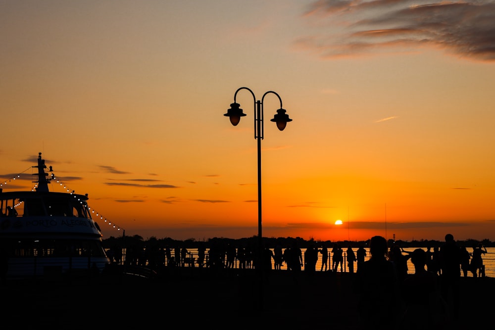 a group of people standing next to a boat at sunset