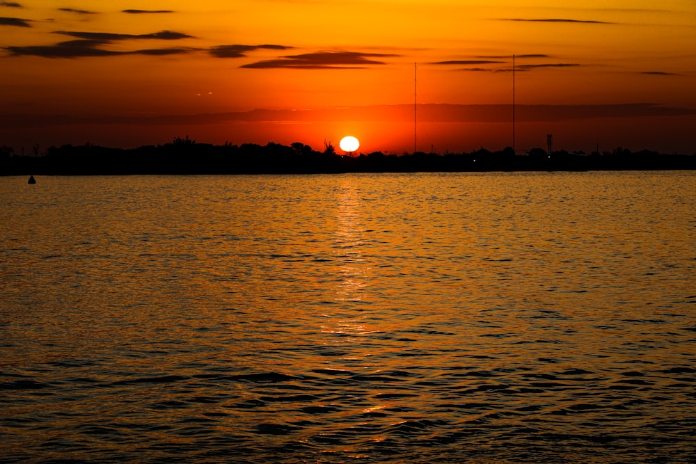 a large body of water with a sunset in the background