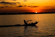 The vivid colors of sunset over Belize’s waters, with a small fishing boat silhouetted on the horizon.