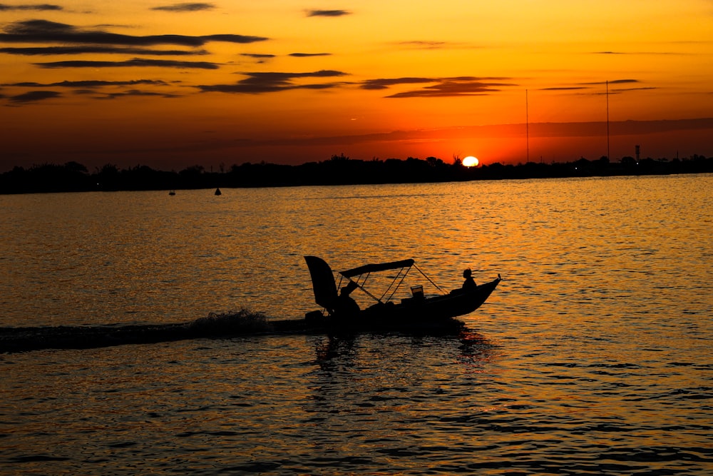 a small boat in the water at sunset