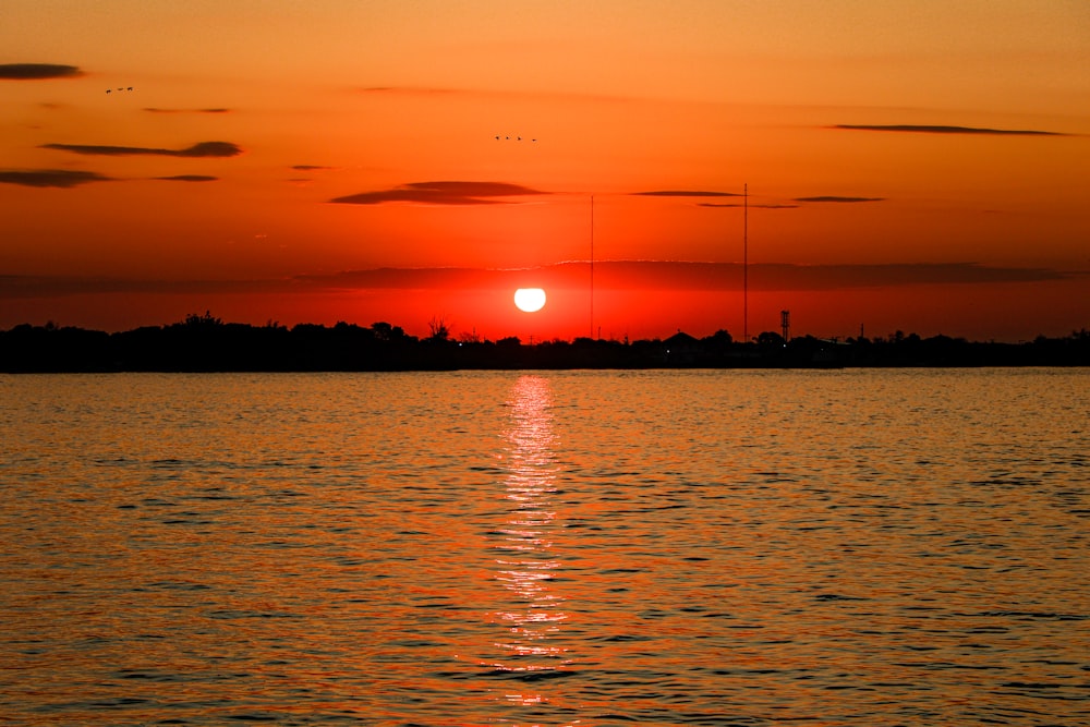 a large body of water with a sunset in the background