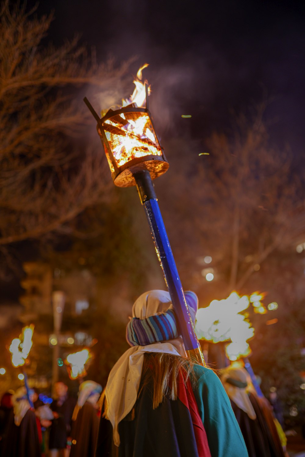 a person holding a lit stick in the middle of a crowd