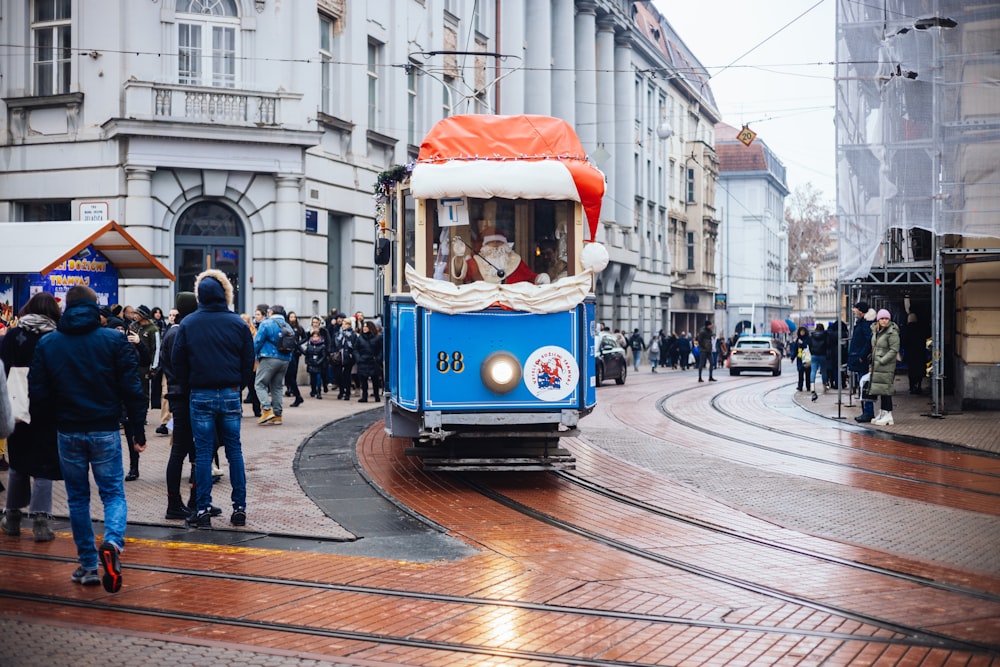 a blue trolley with a red top on a city street