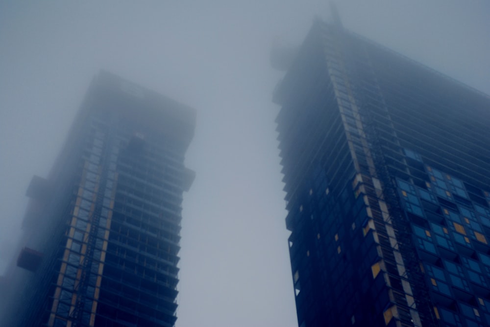 a couple of tall buildings in the fog