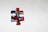 A single jigsaw puzzle piece with a colorful abstract design featuring red, blue, black, and white swirls, placed on a plain light gray background.