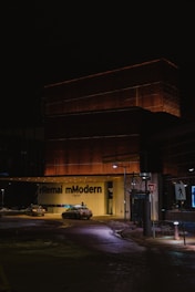 Close-up of illuminated signage on a modern building exterior at dusk.