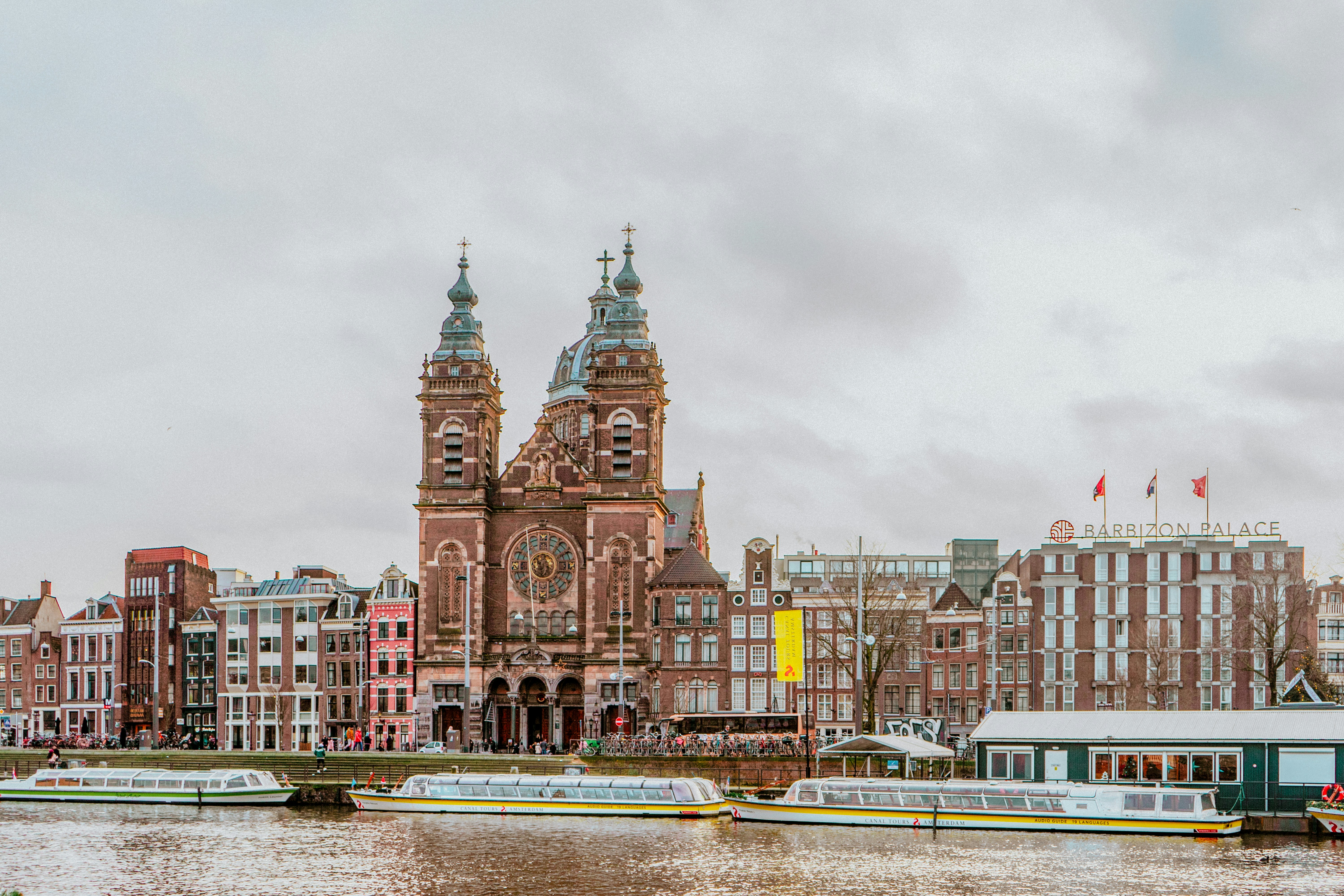a group of boats floating on top of a river next to tall buildings