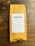 A package of coffee labeled 'DEVOCIÓN', featuring details about its Colombian origin, including variety, region, altitude, and flavor notes. The package is placed on a rustic wooden surface.