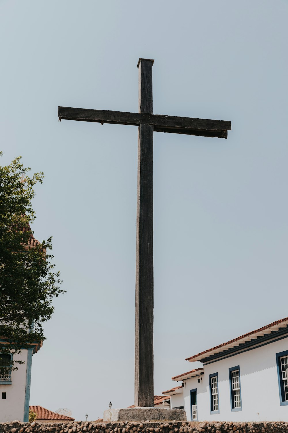 une grande croix en bois au sommet d’un mur de pierre