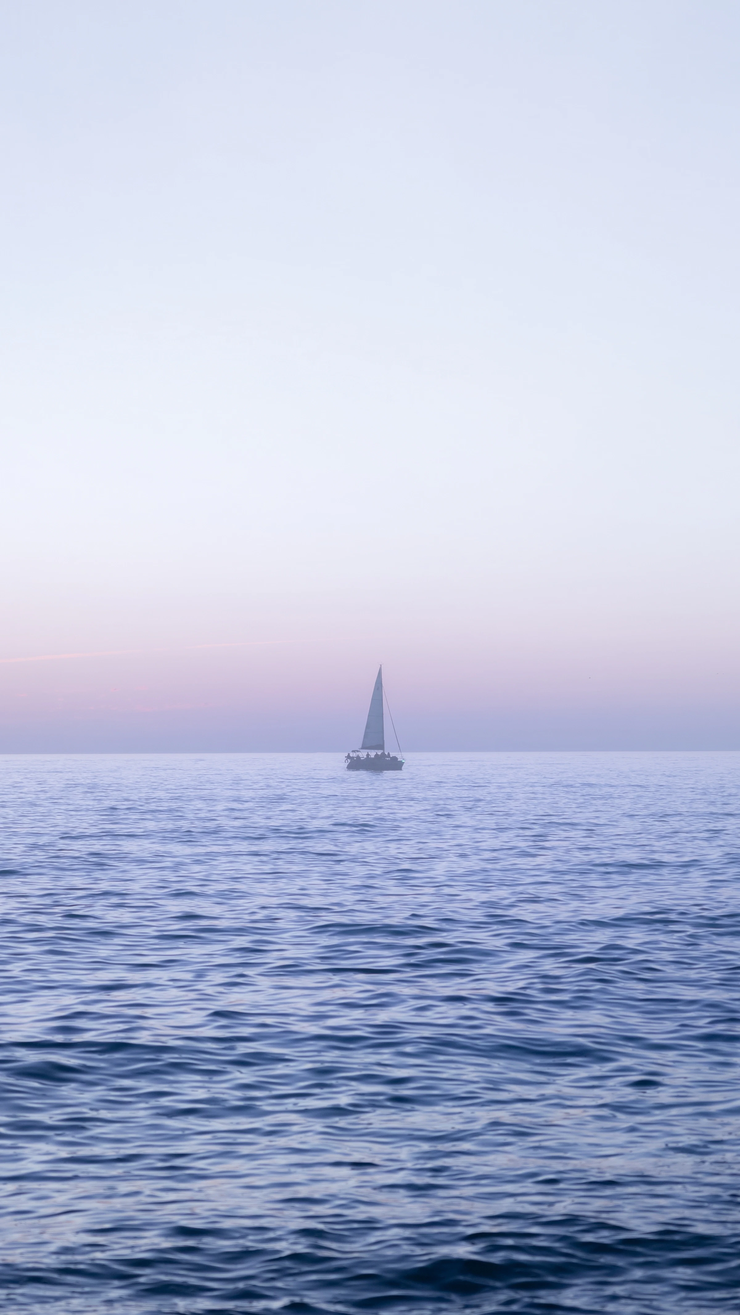 Un velero en las tranquilas aguas frente a Sarasota, Florida, bajo un cielo costero de colores suaves