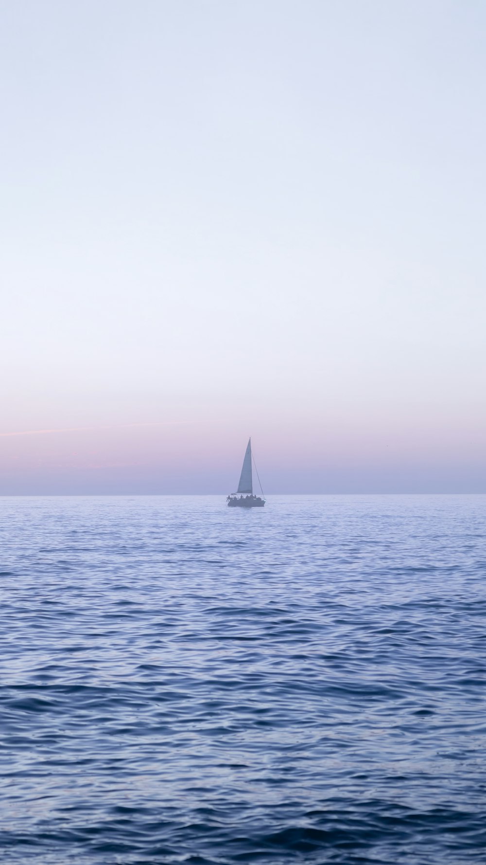 a lone sailboat in the middle of the ocean