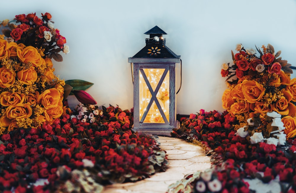 a lantern surrounded by flowers on a stone path