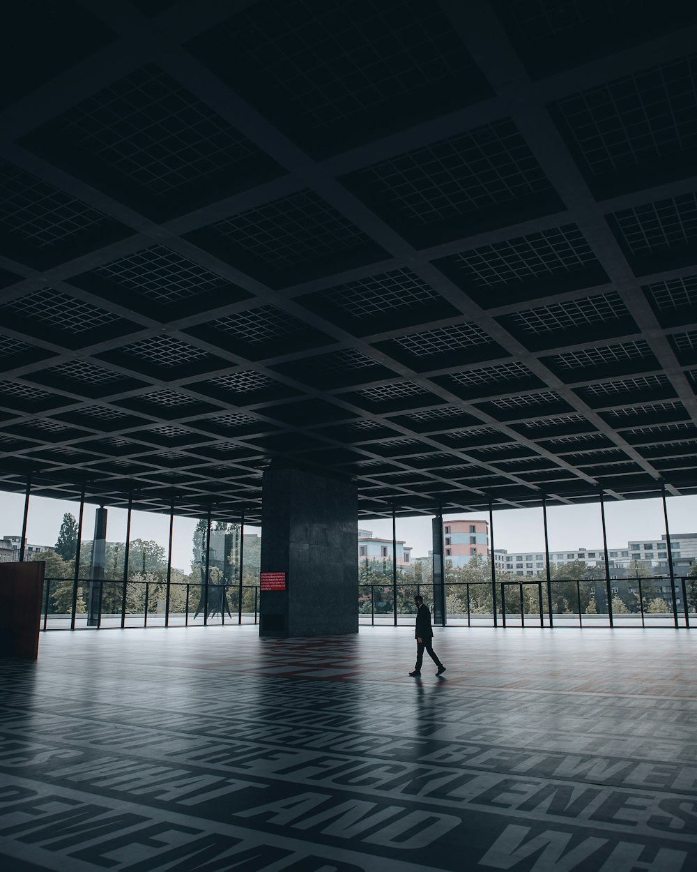 a person walking in an empty room with large windows