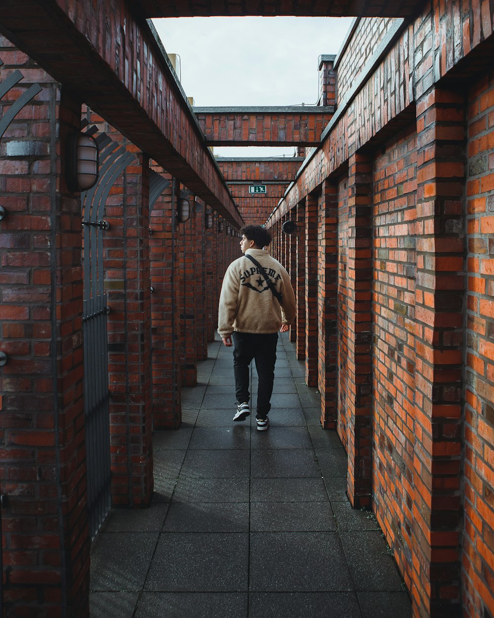 a man walking down a walkway between two brick buildings