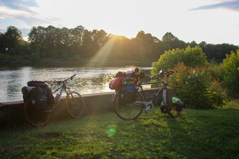 a bike parked next to a river with a backpack on the back