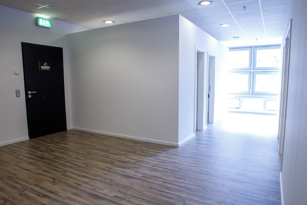 an empty room with a black door and white walls