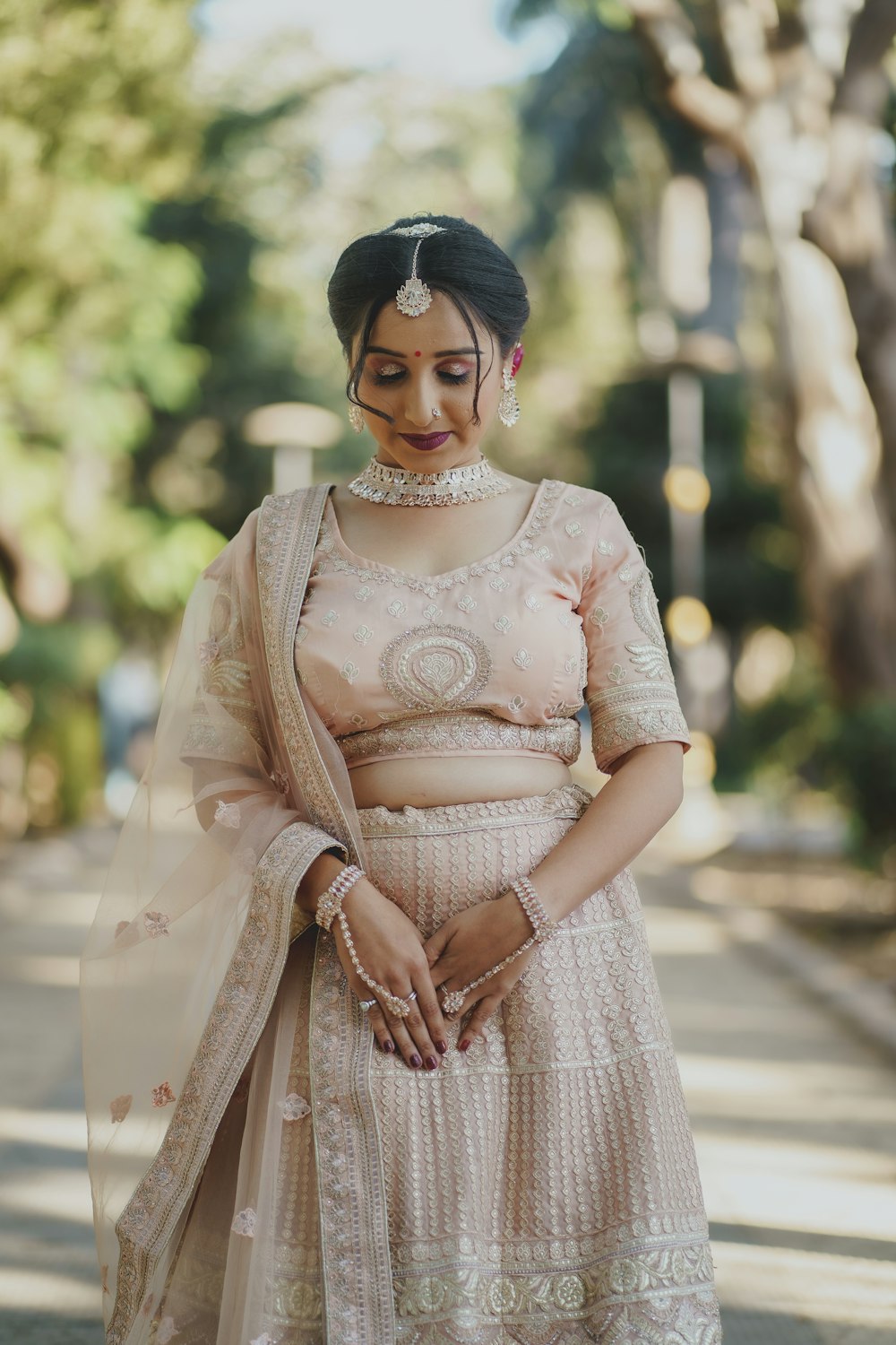 a woman in a pink lehenga standing on a street
