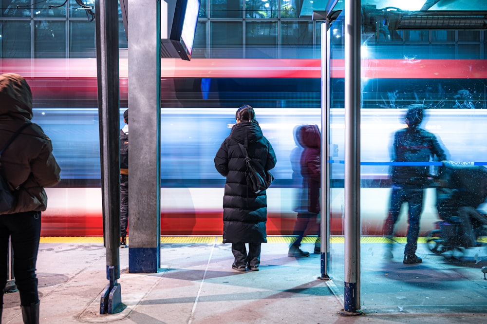 a group of people standing on a sidewalk next to a train