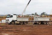 A delivery truck loaded with various building materials parked outside a construction site.