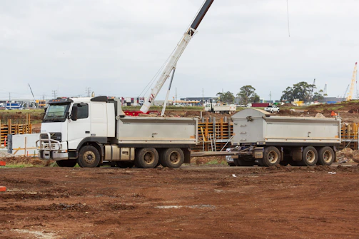 A delivery truck unloading portable restrooms at a busy construction site early in the morning.