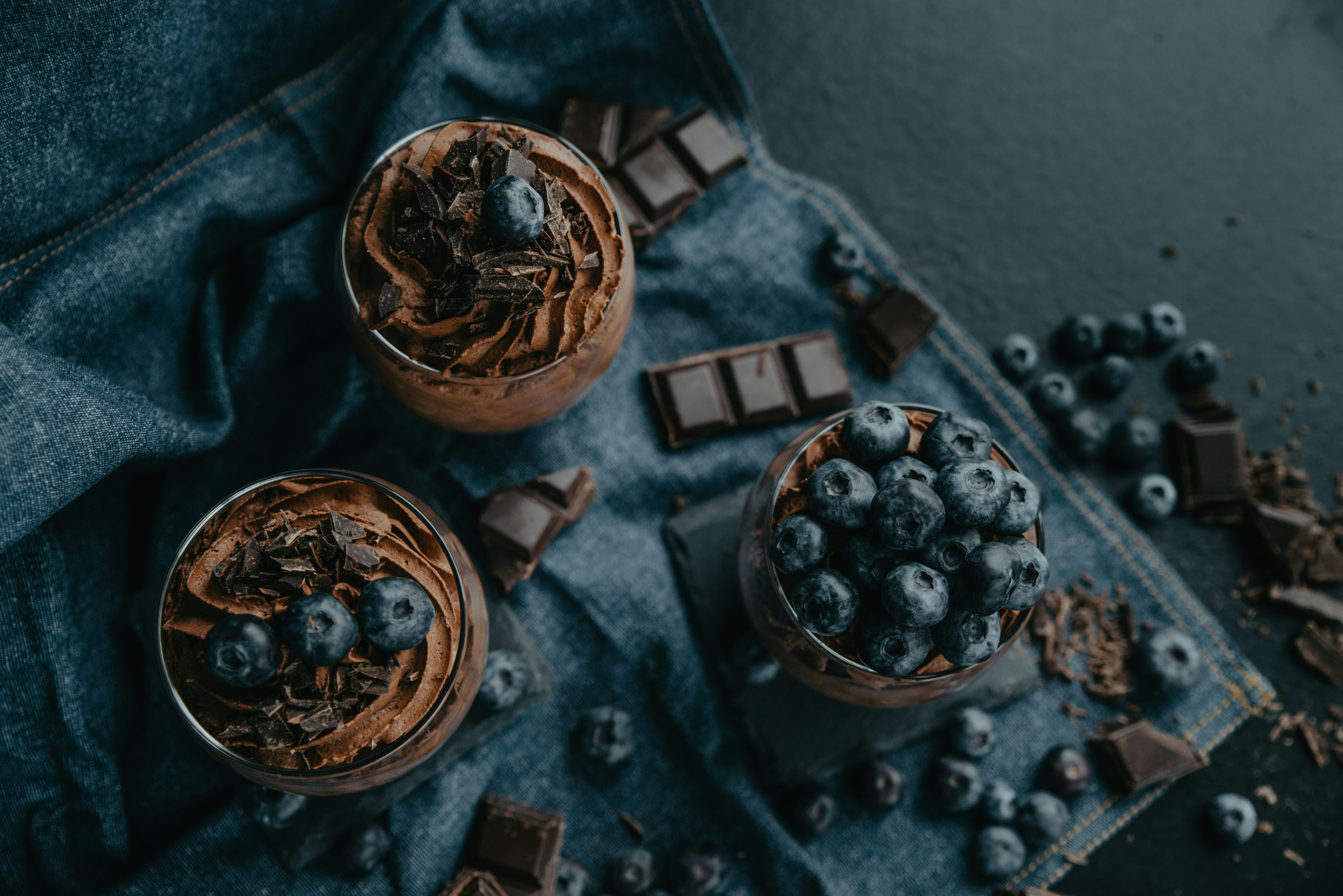 two glasses of chocolate pudding with blueberries on top