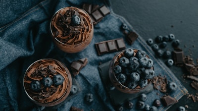 two glasses of chocolate pudding with blueberries on top