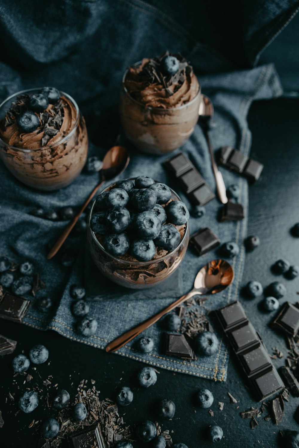 zwei Desserts mit Schokolade und Blaubeeren auf einem Tuch