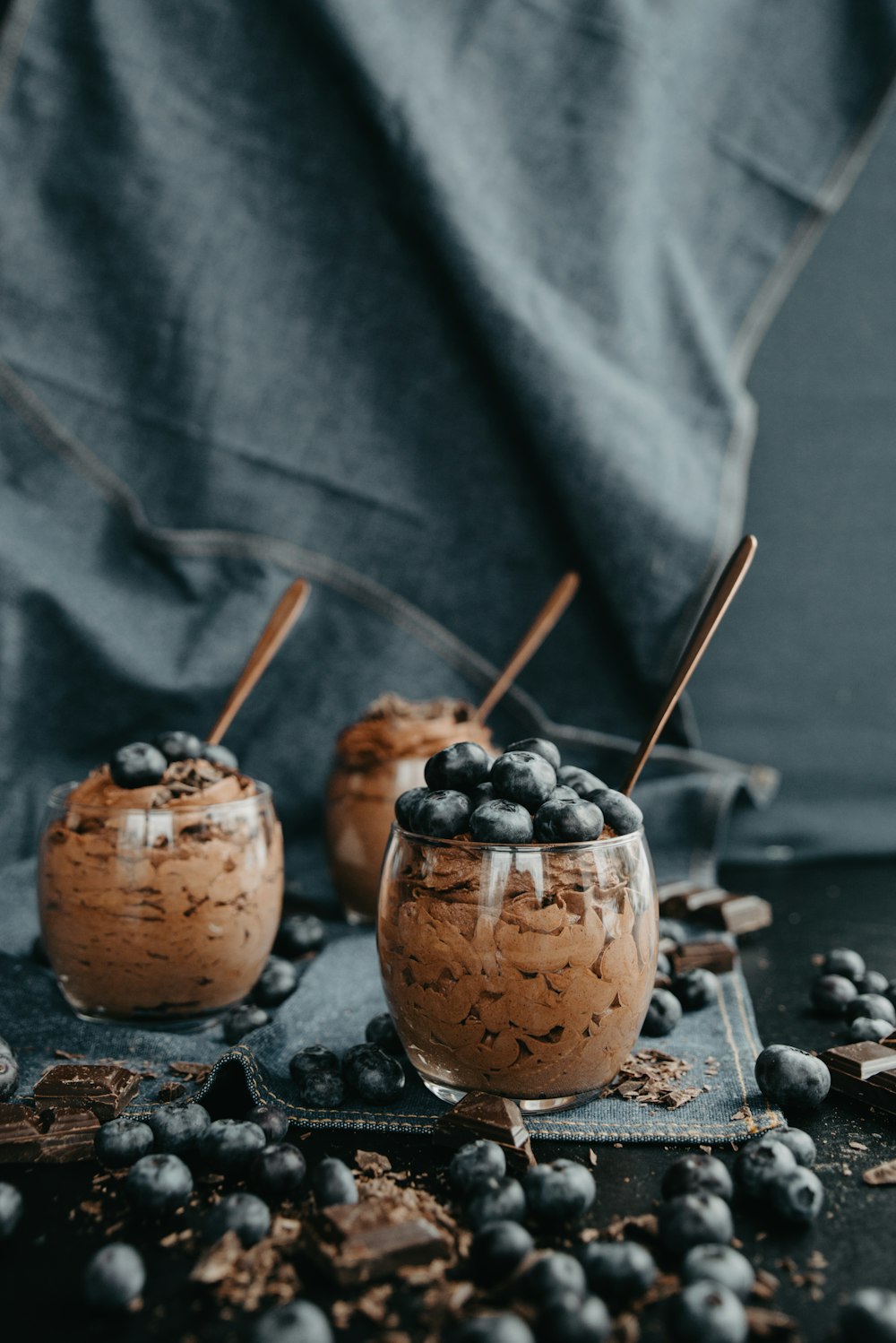 three desserts with chocolate and blueberries on a table