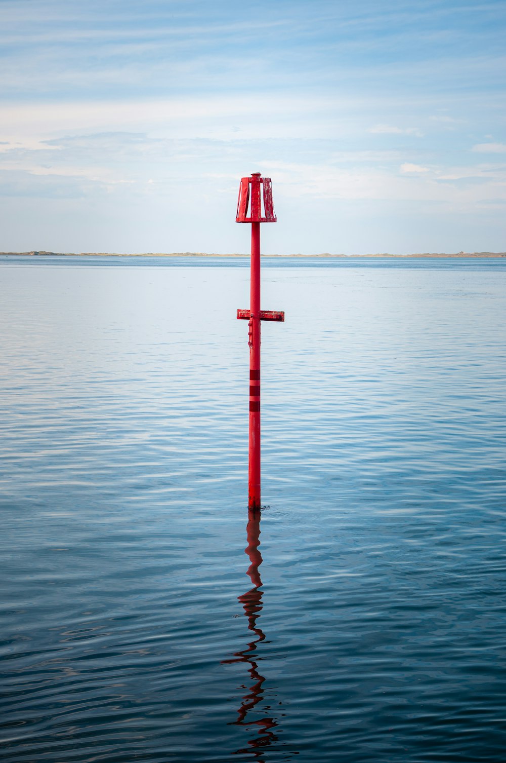 a red pole in the middle of a body of water