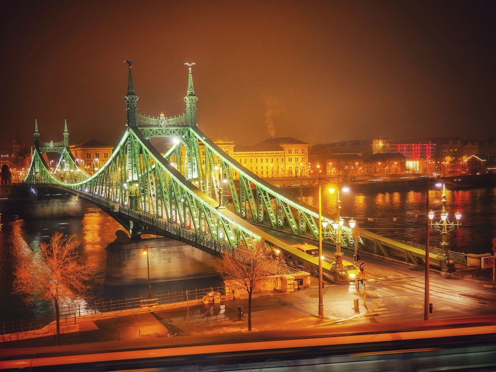 a large green bridge over a river at night