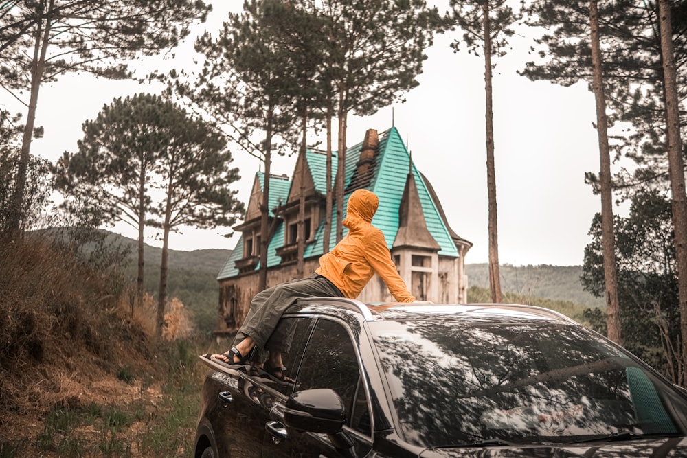 a person sitting on top of a car in front of a house